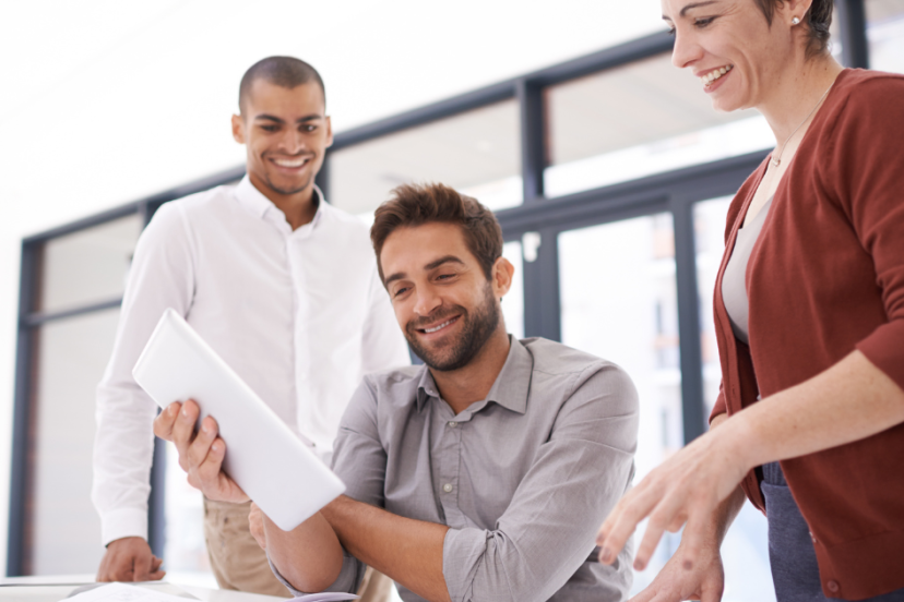 Collaboration tools - image of three young businesspeople working together around an office table using an iPod