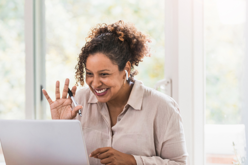 Virtual Meetings - Image of middle aged black women with her hair bunched in the back waving at her virtual meeting friends on her laptop